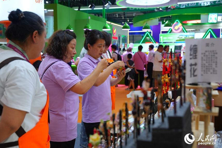 游客在“吉林巧姐”展區(qū)欣賞精美的工藝品。人民網(wǎng)記者 李洋攝