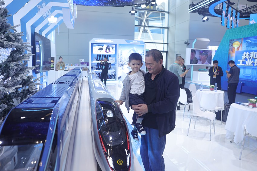 被抱起的小朋友，高興地和高鐵模型來一場“親密接觸”。人民網(wǎng)記者 王海躍攝