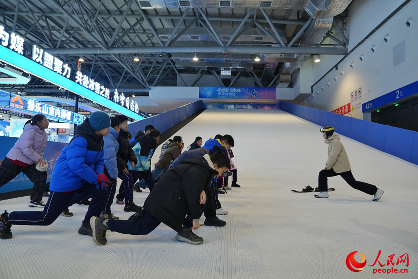 雪博會上，青少年在進行滑雪前的熱身運動。人民網記者 李洋攝