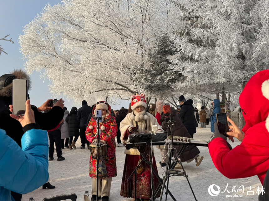 松花江畔，身著特色服飾的表演者在霧凇樹下進行表演，吸引眾多游客舉起手機記錄這一精彩瞬間。人民網記者 李思玥攝
