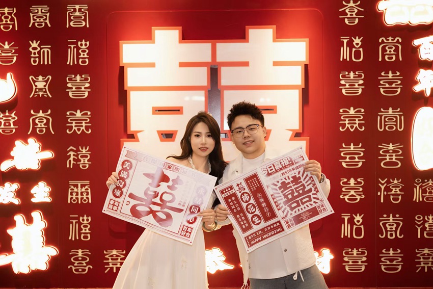 一對(duì)新人在長(zhǎng)春市朝陽(yáng)區(qū)國(guó)貿(mào)喜事城婚姻登記處“百喜墻”前打卡留念