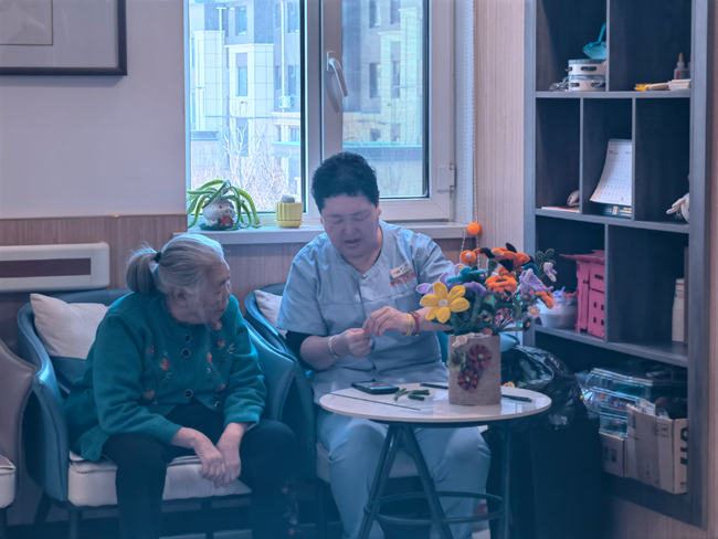 老人在和工作人員學習編織花。人民網記者 馬俊華攝